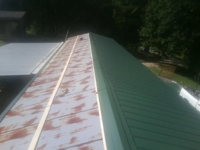 Old rusted panels beside newly installed green metal roofing — Wind Damage Roof Repair by Roofing Brothers in Waynesburg