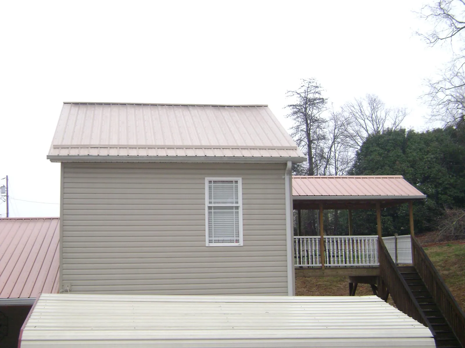 Tan metal roofs on a two story addition and attached porch, from a Roof Replacement job in Waynesburg